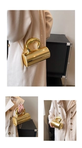 Detailed view of glossy gold cylindrical box bag with mirror finish and metal chain