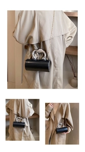 Detail of black acrylic cylinder clutch bag with silver horseshoe handle and gold chain strap