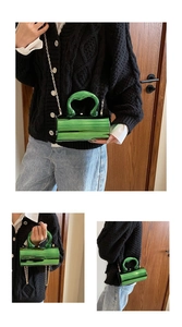 Detail view of metallic green cylinder bag with chunky U-handle and gold chain strap