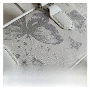Close-up of white leather bag with purple butterfly and silver constellation patterns