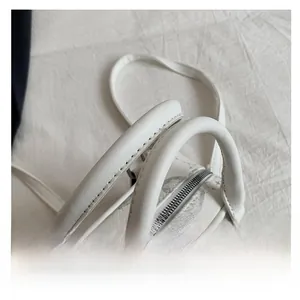 Detail of white leather pillow bag with floral print showing sturdy handles and metal zipper