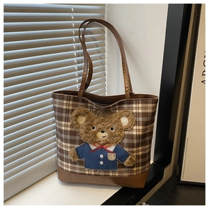 Detail of wool check tote bag with plush bear charm and brown leather shoulder straps