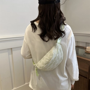 Light green woven crossbody chest bag for women in minimalist half-moon shape style