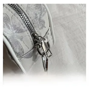Detail of smooth silver metal zipper and floral embossed pattern on small handbag