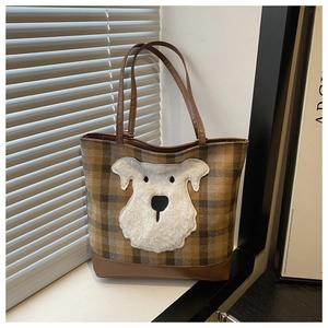Close-up of brown plaid tote bag featuring a 3D plush dog patch and leather base