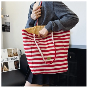 Detailed view of red and white striped fabric tote bag with a handmade logo tag