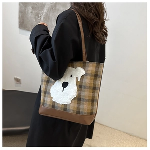 Detail of plaid tote bag featuring a cute plush cartoon puppy patch on textured fabric