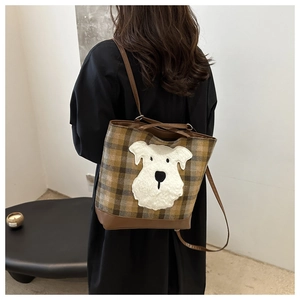 Plaid tote bag with dog embroidery and leather straps shown on a model's shoulder