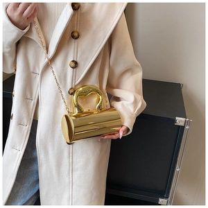 Detail of a golden cylindrical crossbody bag featuring a mirror finish and metal chain
