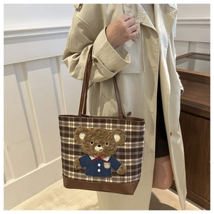 Detail of checkered tweed tote bag with plush bear patch shown on female model