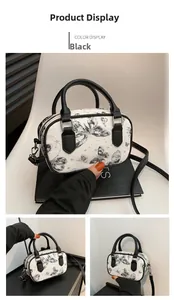Detail view of black butterfly pattern Boston bag with silver hardware and shoulder strap