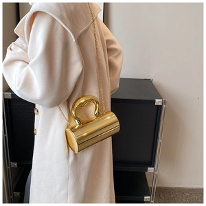Detail of a gold cylindrical acrylic handbag with a chunky circular handle and chain
