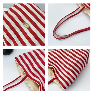 Close-up of red and white striped canvas tote bag showing handmade metal logo and stitching