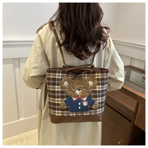 Detail of wool plaid tote bag featuring a cute 3D teddy bear patch and leather straps