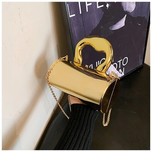 Artistic gold cylindrical acrylic clutch bag with curved handle and chain strap detail