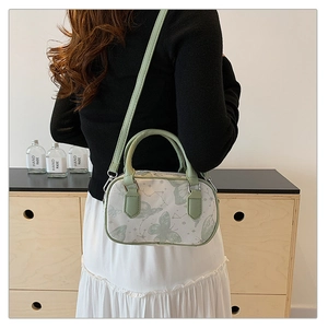 Detail of light green Boston bag with butterfly print worn by model for size reference