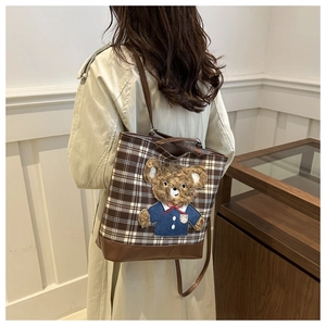 Detail of checkered tweed tote bag featuring a cute 3D teddy bear mascot patch