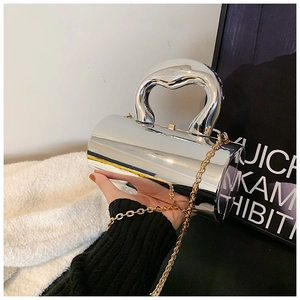 Close-up of silver mirror-finish cylindrical acrylic clutch bag with a metallic handle