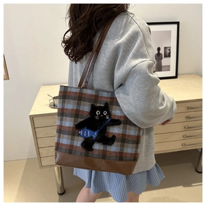 Detail of checkered tote bag with cute 3D cat embroidery and brown leather base