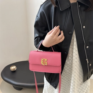 Pink lychee textured crossbody bag with gold buckle and top handle worn by model
