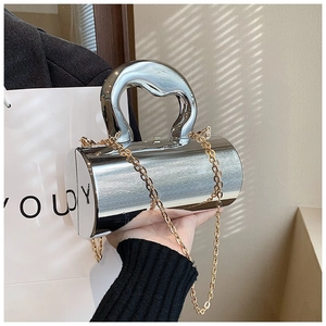 Detailed shot of metallic silver cylindrical handbag with large handle and gold chain