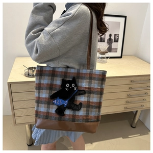 Detail of plaid tote bag featuring 3D black cat embroidery and durable leather strap
