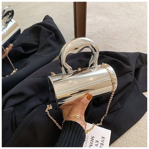 Detailed view of silver metallic cylindrical clutch bag with curved handle and chain strap