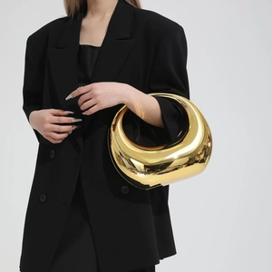 Sac à main doré métallique futuriste à découpe ovale porté par un mannequin chic