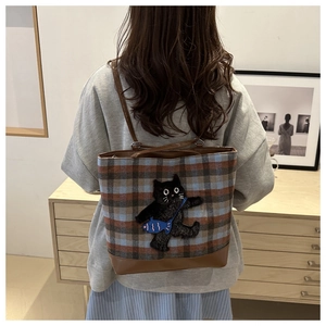 Close-up of a plaid wool tote bag with a cute black cat embroidery and leather straps