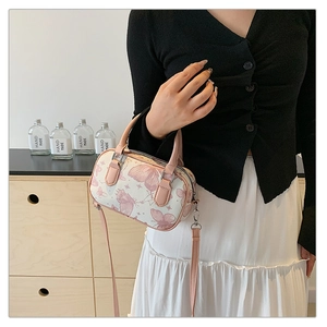 Close-up of mini Boston bag featuring pink butterfly prints and durable leather top handles