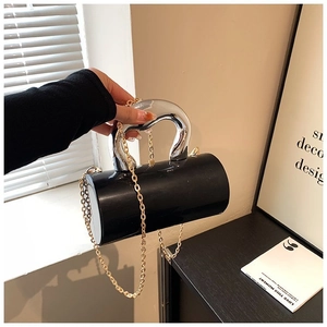 Detail of a black cylindrical acrylic evening bag with oversized silver metal handle