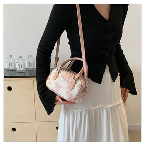 Detailed shot of pink butterfly print boston bag with leather handles and strap