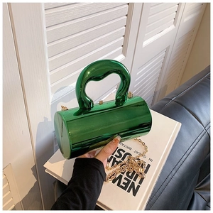 Detail of green acrylic cylindrical bag with glossy finish and gold chain strap