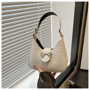 Dettaglio borsa a tracolla beige motivo coccodrillo con fibbia metallica a fiocco