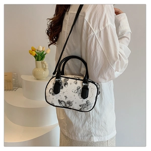 Lifestyle shot of white embossed crossbody bag with butterfly patterns and black handles
