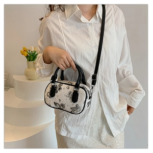 Detail view of mini Boston bag featuring black butterfly patterns and silver hardware