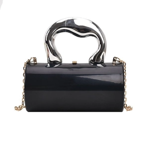 Macro view of a cylindrical black acrylic box bag featuring a silver sculptural handle