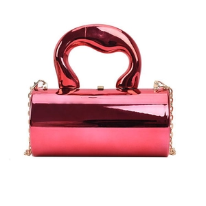 Macro view of metallic rose red cylindrical evening bag with gold chain and artistic handle