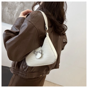 Dettaglio borsa bianca texture coccodrillo con fiocco argento indossata sulla spalla