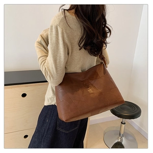 Detail of dark brown tote bag showing geometric patchwork and knotted shoulder strap