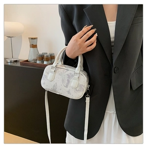 Detailed view of white butterfly print boston bag with leather texture and straps