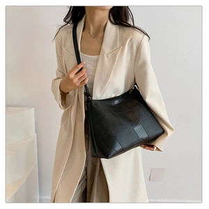 Detail view of black tote bag featuring large quilted leather pattern and smooth strap