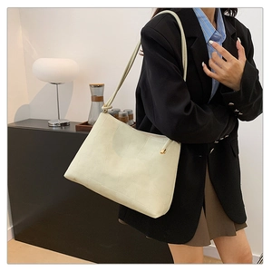 Detail of cream tote bag featuring geometric embossed texture and elegant gold accents