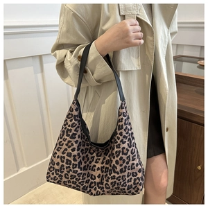 Hobo style leopard print tote bag with black strap shown on model in a modern interior