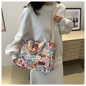Close-up of floral canvas tote bag featuring brown leather FASHION tag and fabric straps