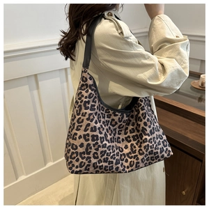Sac cabas léopard avec bordures noires et bretelles porté sur un trench-coat beige