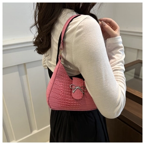 Dettaglio della borsa rosa con stampa coccodrillo e decorazione a fiocco argentato