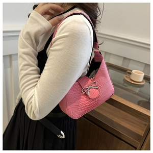 Détail d'un sac à bandoulière rose à motif crocodile avec nœud métallique argenté