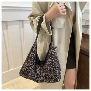 Détail du sac hobo léopard avec bandoulière noire porté sur un trench-coat beige