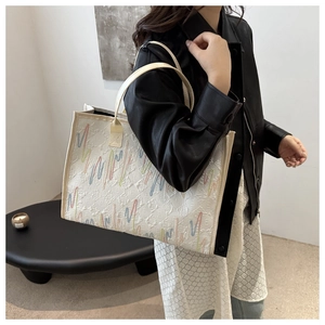 Vue détaillée du grand sac cabas blanc avec broderie ondulée colorée et lettrage de marque